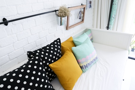Colorful pillows on a sofa with white brick wall in backgroundの写真素材