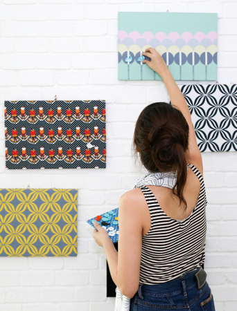 Asian girl decorate her home with magnets and pattern on white brick wall background