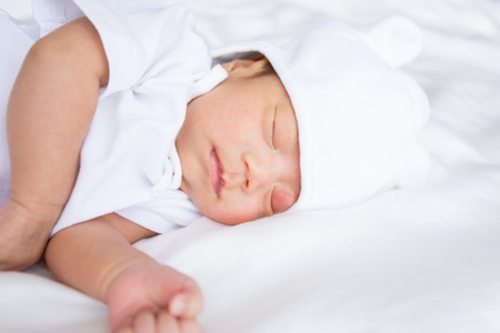 Asian infant baby lying on white bed backgroundの写真素材
