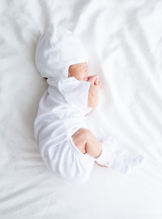 Asian infant baby lying on white bed backgroundの写真素材
