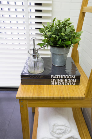 Interior decoration of modern contemporary toilet with wooden chair, books, and towelの写真素材
