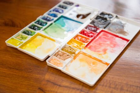 Paintbrush and paint palette with colorful mixed watercolorの写真素材