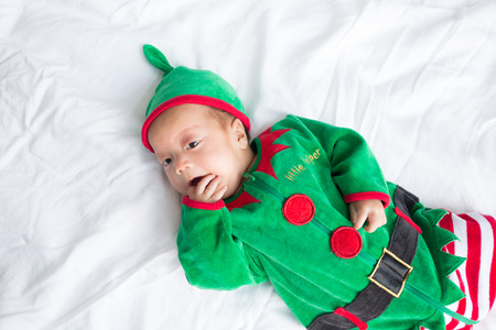 Baby in green elf costume for christmas holiday on white backgroundの写真素材