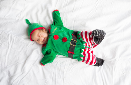 Baby in green elf costume for christmas holiday on white backgroundの写真素材