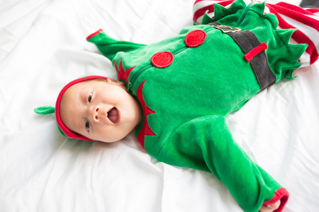 Baby in green elf costume for christmas holiday on white backgroundの写真素材