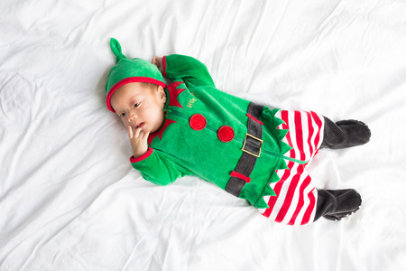 Baby in green elf costume for christmas holiday on white backgroundの写真素材