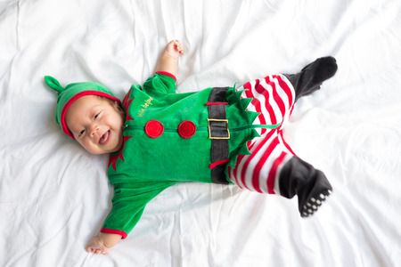 Baby in green elf costume for christmas holiday on white backgroundの写真素材