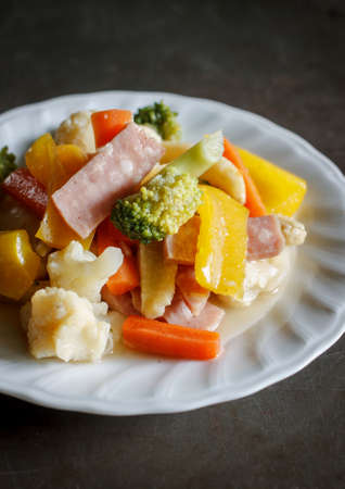 Stir-fried vegetables with ham served in white plate and grunge metal backgroundの写真素材