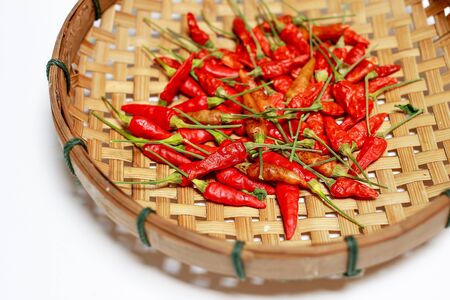 Red dry chilli in bamboo basket on white backgroundの写真素材