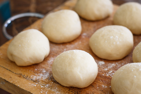 Small balls of fresh homemade pizza dough on floured wooden boardの写真素材