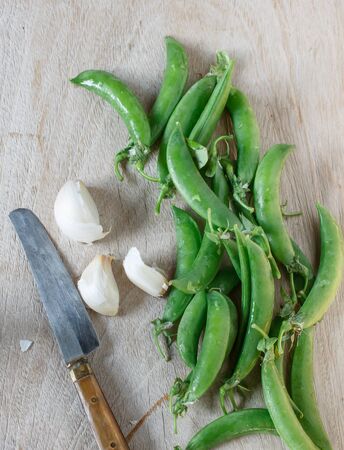ripe pods of green peas on a white wooden tableの写真素材
