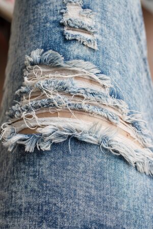Closeup of tear in old worn out jeans in vintage toneの写真素材