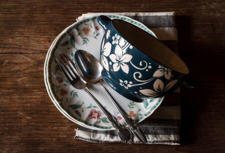 Antique decorative dinner plate and vintage pewter fork on distressed wood with decorative carved border.Still life image dark toneの写真素材