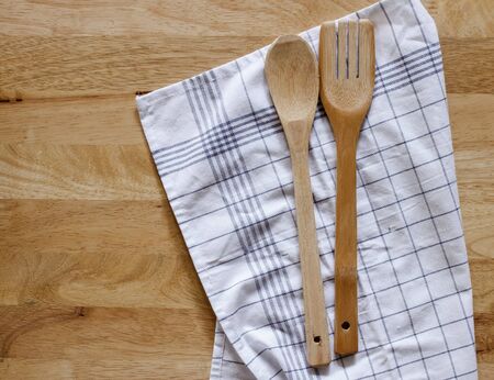 Serving spoons on checkered cloth lying on wooden surfaceの写真素材