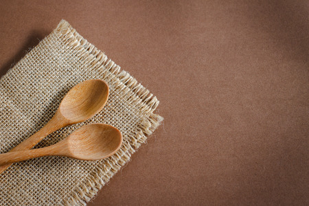 Serving spoons on burlap cloth on wooden surface. Image brown tone.の写真素材