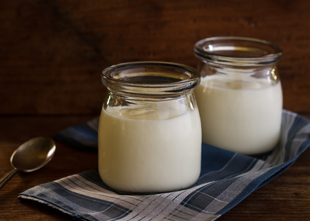 Greek yogurt in a glass jars on wooden background, still life image dark tone.の写真素材