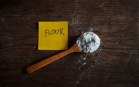 Flour on wood spoon with grunge table background, image dark tone and soft focus.の写真素材