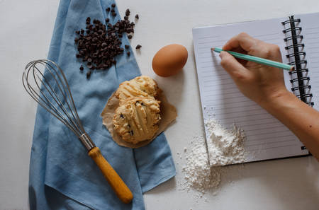 Delicious homemade chocolate butter cookies with dark chocolate, hand whisk, flour, egg and paper note for write recipe.の写真素材