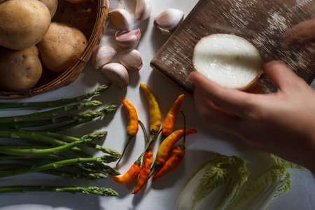 Fresh ingredients for cooking in rustic kitchen: chinese cabbage, garlic, onion and chili with hand moving.の写真素材