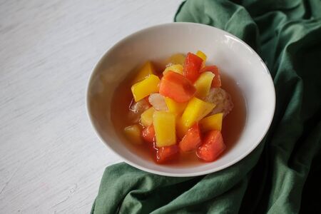 fruit salad in syrup served in white small cup and green napkin.の写真素材