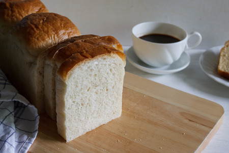 Sliced white bread with cup of coffee put on white wood .
