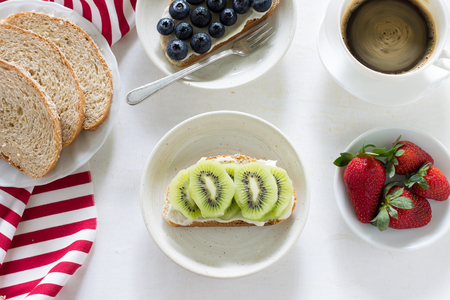 whole wheat bread, cottage cheese, strawberry and blueberry served with black coffee on white wood.の写真素材