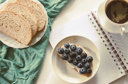 whole wheat bread, cottage cheese, blueberry served with black coffee on white wood.