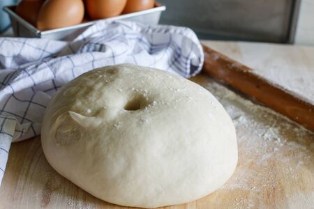 Dough for pizza or bread and rolling-pin on wooden table