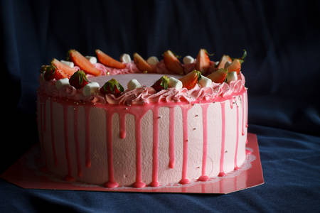 Delicious Pink buttercream cake top with fresh strawberry and marshmallow put on blue cloth background.の写真素材