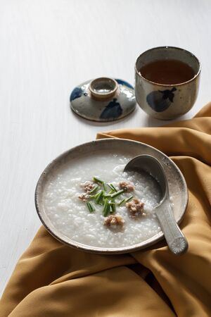 Rice porridge with pork put on white wooden table, rustic food.の写真素材
