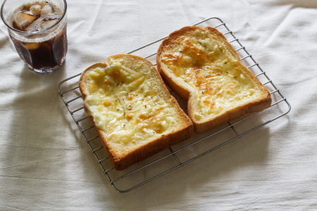 Toasted bread with garlic and cheese, glass of cold iced coffee in cloth background.の写真素材