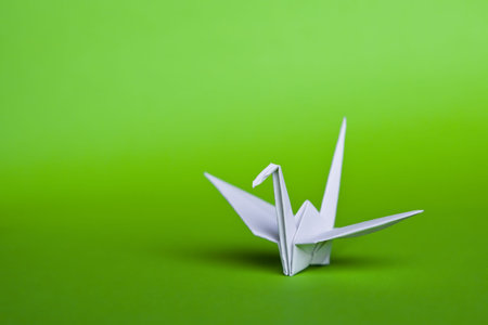 A white origami crane on a green backgroundの写真素材