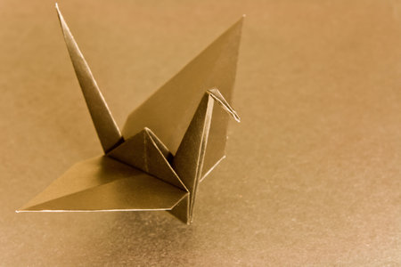 An origami bird on a metallic colour background. Shallow depth of field. Focus on the head of the bird.の写真素材
