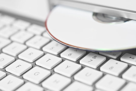 Close-up of a white CD and a computer keyboardの写真素材