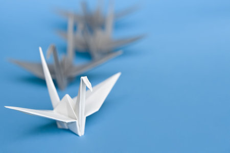 A group of white and grey origami birds forming a queueの写真素材