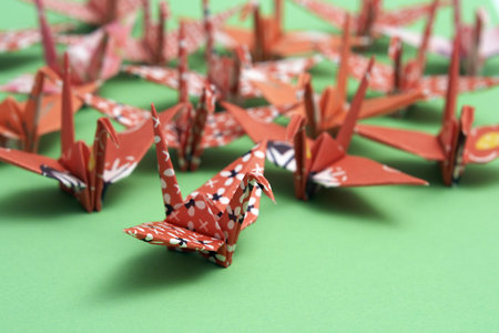 A group of origami birds on a green backgroundの写真素材