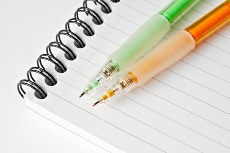 2 colourful mechanical pencils on top of a notebook 