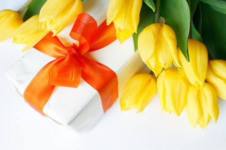 A white chocolate box surrounded by yellow tulipsの写真素材