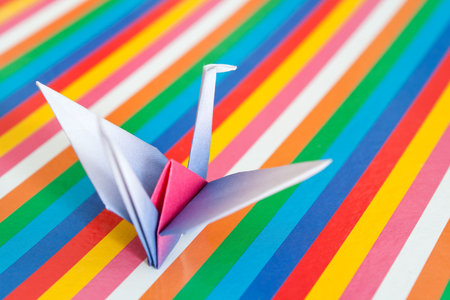 A single paper bird on a colorful stripes background. Shallow depth of field. の写真素材