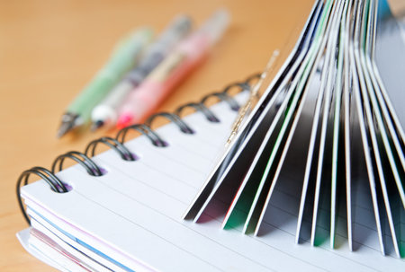 Credit cards, spiral notebook and a few pens on a desk. Shallow depth of field. の写真素材