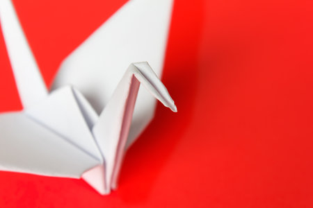 A white paper bird on a red background, shallow depth of field  の写真素材