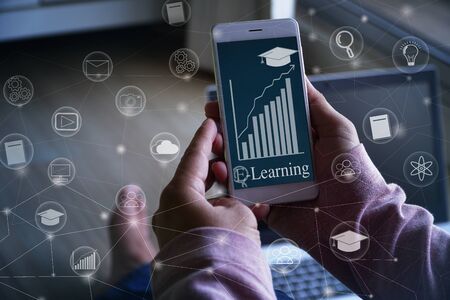 Online learning concept -  Hand hold smartphone  and finger pressing on screen with graph , education icon and internet or technology connection lines in blue toneの写真素材