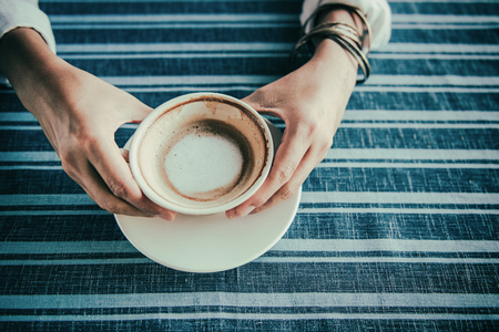 Asian woman  hands holding cup of coffee on  table.Focus on the coffee cupの写真素材