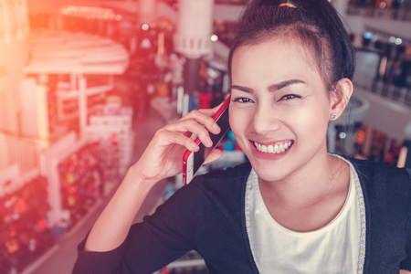 Picture of Asian woman talking on the phone while shopping at a shopping mall.Focus on faceの写真素材