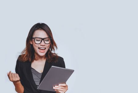 Asian woman smiled in a happy mood as she stared at her tablet on white backgroundの写真素材