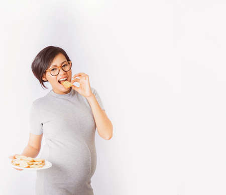 Asian pregnant woman eating biscuits In a happy mood, On white background.Focus on face