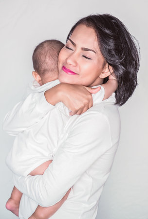Asian woman and son hugging each other In a happy mood, Focus on mom's faceの写真素材