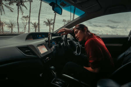 asian woman sleeping in car, attractive girl sitting in automobile, outdoors raining. lifestyle and people concept.の写真素材