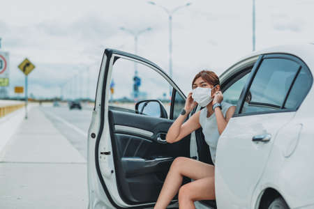 Asian woman   wearing protective face mask protection safety before getting out of the car during coronavirus covid-19 outdoor curfew pandemicの写真素材