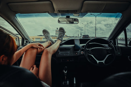 women sitting on passenger seat in car with feet on car dashboard. Young woman relaxing in car. on summer travel vacation. traveling concept.の写真素材